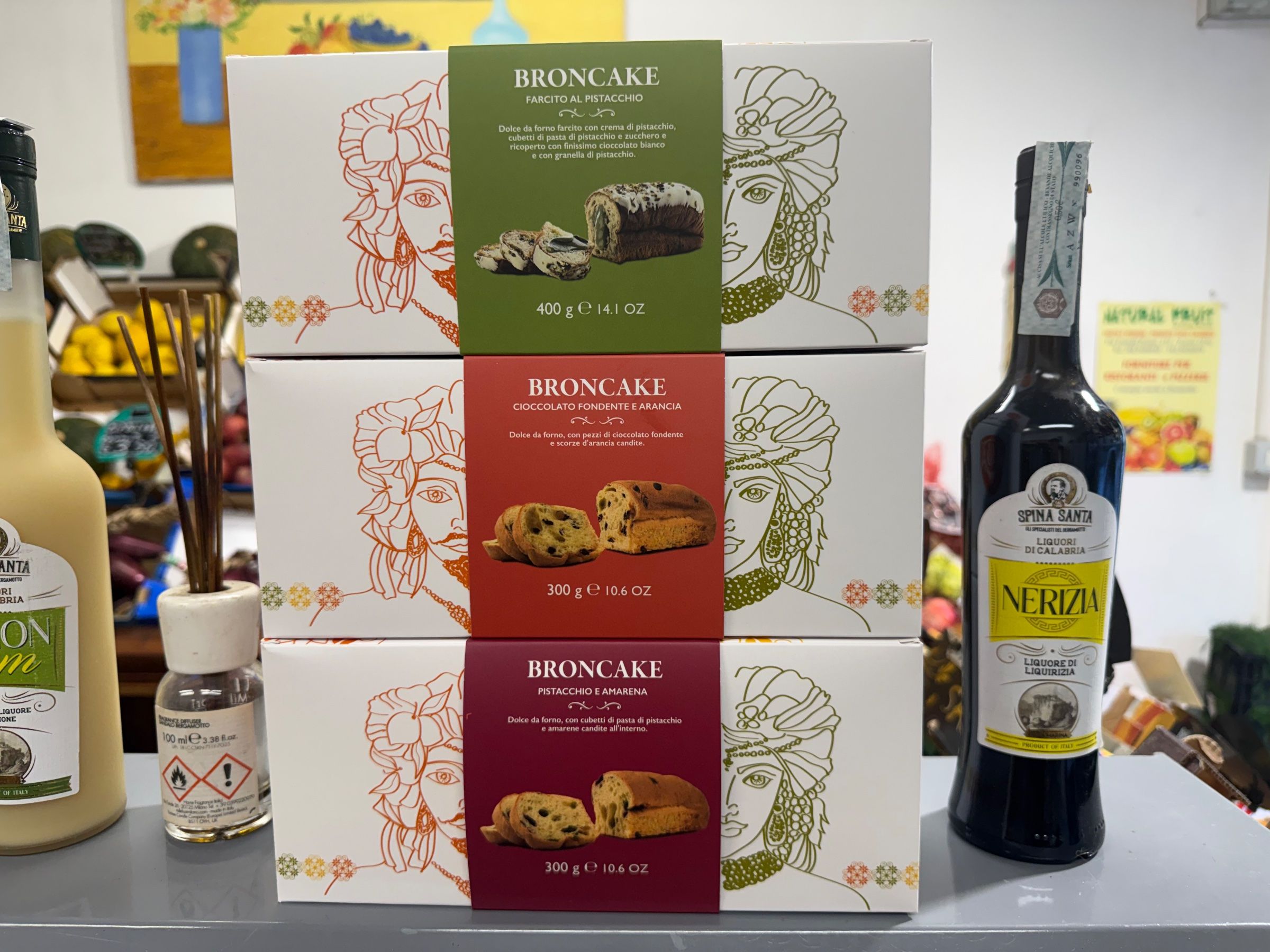 Le confezioni di Broncake sul bancone di Natural Fruit: il dolce da forno farcito al pistacchio, quello al cioccolato fondente e arancia e quello al pistacchio e amarena, fra le bottiglie dei liquori di Calabria